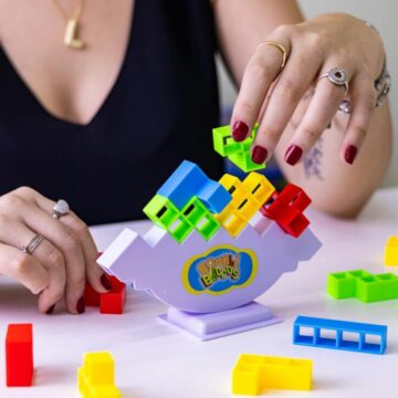 Woman playing with colorful blocks, showcasing balancing game on table in Sao Paulo.